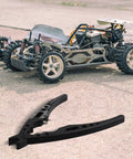 Aluminum Alloy RC Ball Head Pliers With Shock Absorber Multi Function Hand Tool beside model car on pavement.