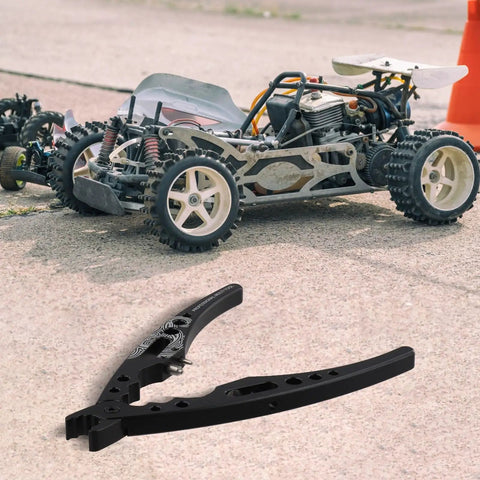 Aluminum Alloy RC Ball Head Pliers With Shock Absorber Multi Function Hand Tool beside model car on pavement.