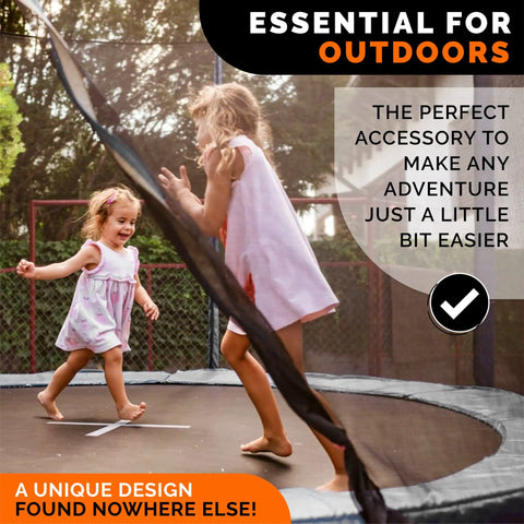 Two young girls playing on a trampoline, outdoors, with sunlight filtering through trees, showcasing the joy of outdoor play.