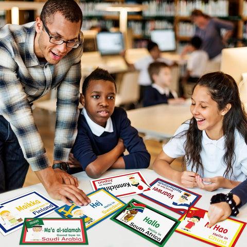 Teacher with students using 30 Pieces Greetings From Around The World Language Cutouts For Classroom Decor And Multicultural Learning Materials Kid Friendly Eye Catching Colorful Designs Perfect For Preschool To Elementary School And Homeschool at a school desk.