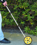 Measuring Wheel, Extendable Accurate Portable Metric Rolling Distance Tool in use on pavement with adjustable rod.