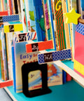 Colorful bookshelf with books labeled using Fun Dots Washi Tape 6-Roll Set, .59 in x 393 in Decorative Craft and Planner Tape.