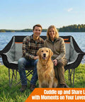 Heavy Duty Double Camping Chair For Two Adults 650 Lbs Capacity Fully Padded Loveseat Folding Outdoor Chair by a lake with couple