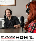 Two people podcasting wearing Dope Over Ear Studio Headphones With Closed Back Design, microphones and laptop on table.
