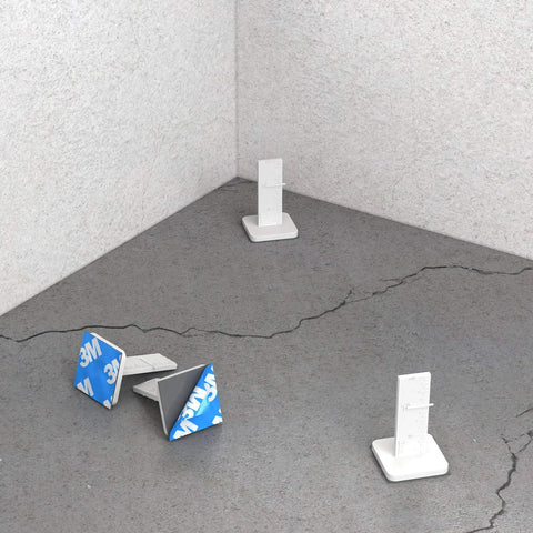 Model 82 289 Leveling Pins 50 Pack For Concrete Pours With Self Adhesive Backing shown on a cracked concrete surface