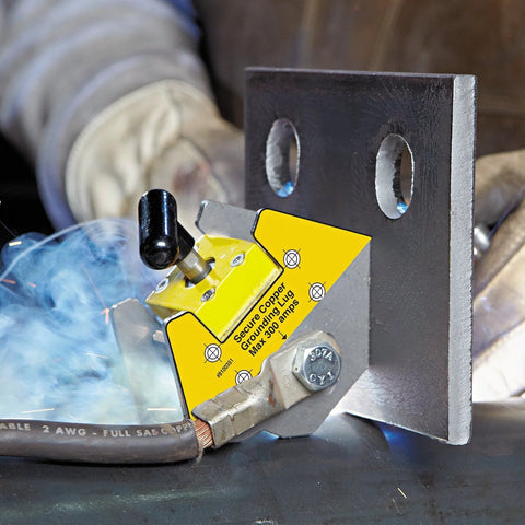 Front view of yellow Magswitch mini multi-angle welding magnet with grounding clamp holder on a metal plate; arc sparks.