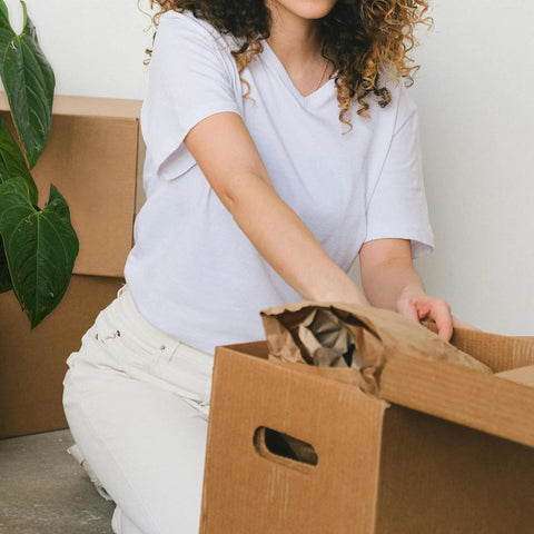 Person packing with Brown Kraft Packing Paper Sheets For Moving And Shipping 1500 Count 1375 Feet Total in a cardboard box.