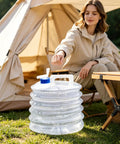 Person camping with 10L Collapsible Water Container With Spigot For Camping And Hiking next to a tent and table