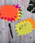 Eye Catching Burst Star Neon Signs Set, 60 Piece Pack in Six Fluorescent Colors with black marker on wood surface