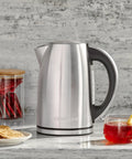 Stainless Steel Electric Kettle 1.7 Liter Cordless Design With 1500 Watt Power For Fast Boiling Tea Coffee And Hot Chocolate next to tea and cookies.