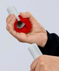 Hand using Pipe Cutter For Plastic Pipes 20 To 50 mm That Cuts Without Shavings, Ergonomic Handle, cutting a white plastic pipe.
