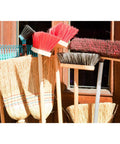 Ten Pack Wall Mount Organizing Spring Clamps For Tools, Rakes And Brooms holding various brooms and rakes against a wall.