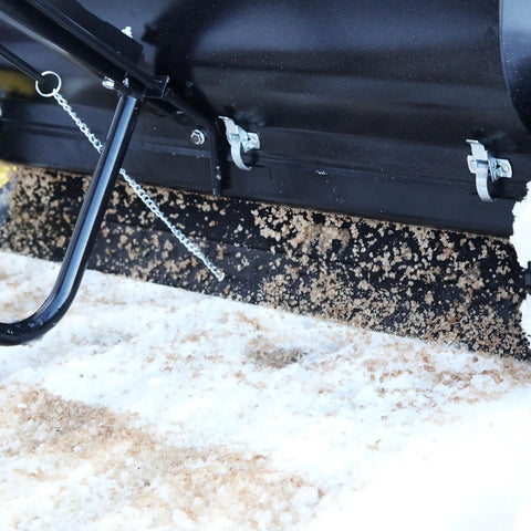 Close-up of Spyker P70-12010 Commercial Drop Spreader dispensing on snow, showing powder-coated steel frame and precision spreader.