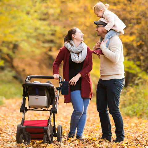 Family in a park with a stroller featuring Universal Stroller Cup Holder With Phone Holder, adjustable drink holder attached.