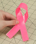 Holding neon pink duct tape piece folded like ribbon on craft grid, Neon Pink Duct Tape 1.88 Inch By 15 Yard Heavy Duty Roll For Repairs
