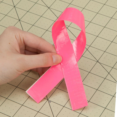 Holding neon pink duct tape piece folded like ribbon on craft grid, Neon Pink Duct Tape 1.88 Inch By 15 Yard Heavy Duty Roll For Repairs