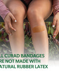 CURAD beige adhesive bandage applied to knee; person sitting outdoors