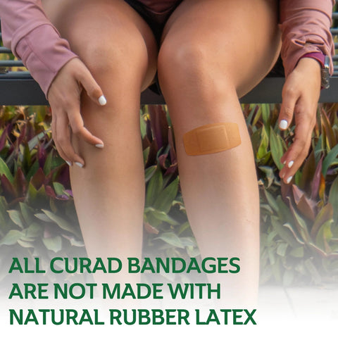 CURAD beige adhesive bandage applied to knee; person sitting outdoors