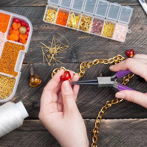 Using 4 Piece Jewelry Pliers Set For Beading And Jewelry Making Including Needle Nose Pliers, Round Nose Pliers, Bent Nose Pliers And Wire Cutter Handy Tools Kit For Bracelet Craft, Wire Wrapping, And DIY Jewelry on a heart-shaped bead with chain and bead organizer visible.