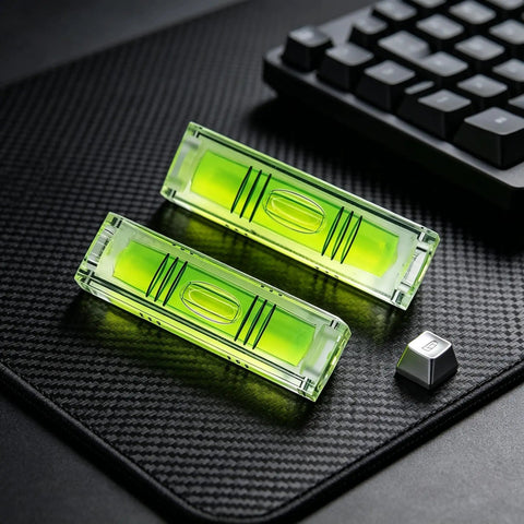 2 Pack Magnetic Mini Bubble Level Tool 2 Inch, Small Pocket, featuring strong magnet and measurement grid, placed on a textured surface.