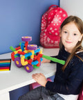 Child playing with 136-Piece Tubular Pipes And Spout STEAM Interlocking Building Block Set on a desk.