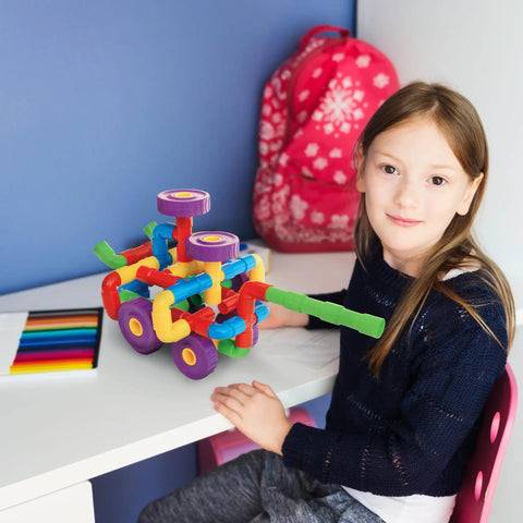 Child playing with 136-Piece Tubular Pipes And Spout STEAM Interlocking Building Block Set on a desk.