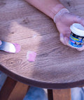 Close-up of Professional Grade DryDex Wood Filler 55 Oz tub being applied to wooden table surface.