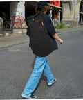 Person walking with a Heavy Duty 12 Inch Practice Pad Backpack That Stays Totes Waterproof securely carrying drum gear.