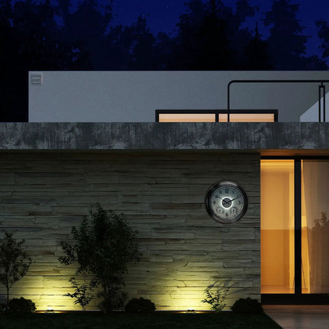 LED Illuminated Outdoor Clock With Temperature And Humidity, 24 Inch Black, installed on a patio wall at night