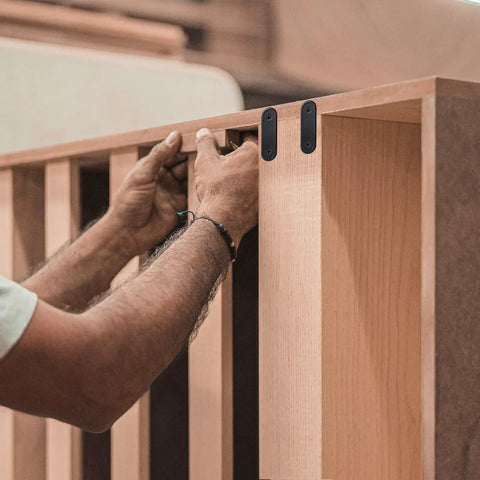 Hands installing sturdy stainless steel straight braces for wood furniture mending plates multiuse black metal brackets.
