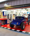 Blue vintage car on red interlocking garage tiles with tools and cabinets, Interlocking Garage Floor Transition Edge Border For Graphite Tiles 12 Inch Beveled Border Pieces, Easy Install, Compatible With RaceDeck, GarageTrac, And GarageDeck Tiles, 11 Pack Male, visible inside open garage.