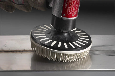 Hand using Roloc Bristle Disc Kit 982BS, 2 Inch Pack Of 5 for deburring metal surface with flexible bristles and abrasive grain.
