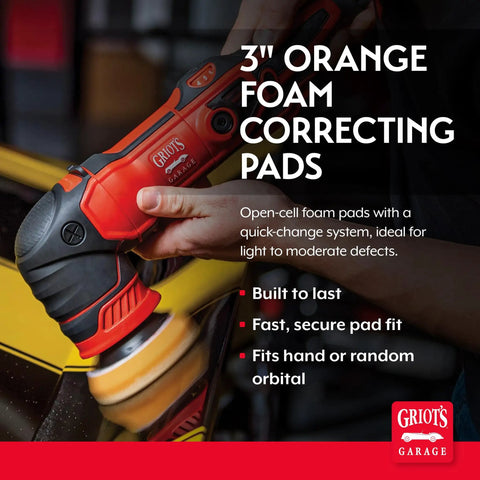 Close-up of 3 inch orange foam correcting pads attached to polishing tool, removing light to moderate paint defects on car surface.