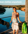 Heavy Duty Travel Laundry Sack Featuring Slick Inner Washboard Grooves Keeps Your Everyday Threads Fresh Camping Trips RV Adventures And Hotel Stays Lightweight Quick Rinse Gear Bags Cut Laundromat Headaches Fast, displayed by a smiling person with clean clothing hanging outdoors.