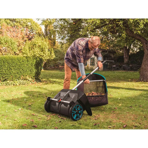 Man using Durable Lawn Sweeper For Leaves And Grass Clippings, No Fuss Maneuvering 3.2 Cu Ft Mesh Hopper on green lawn