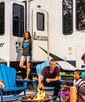 People enjoy a campfire outside an RV decorated with a Funny Camping Decor Sign For RV And Camper Interiors, Easy Install Wall Art.