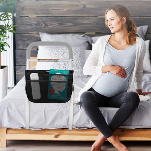 Pregnant woman sitting next to Bed Assist Rail For Seniors, Adjustable With Foam Padded Handle, Non Slip Under Mattress Base
