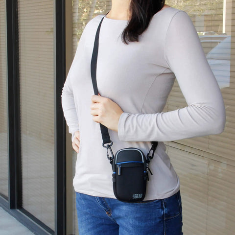 Person wearing Weatherproof Compact Camera Case With Padded Interior And Accessory Pockets, slim digital pouch, black.