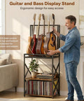 Show Off Your Sweet Guitar Collection With This Super Cool 3 Tier Music Stand. Holds Five Strummers Safe And Sound. Built-In Vinyl Record Spinning Rack For That Retro Vibe. Sturdy, Stylish, And Ready To Rock Your Home Or Studio Space Today. - Man adjusting guitars on ergonomic bass display stand with vinyl records below.