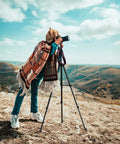 Photographer using 71 Inch Aluminum Camera Tripod Stand With Wireless Remote And Phone Holder on a windy hilltop