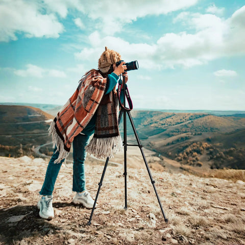 Photographer using 71 Inch Aluminum Camera Tripod Stand With Wireless Remote And Phone Holder on a windy hilltop