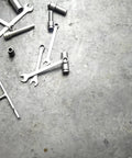Wrenches and sockets scattered on a concrete floor, tools for mechanics and auto technicians in a workshop setting.