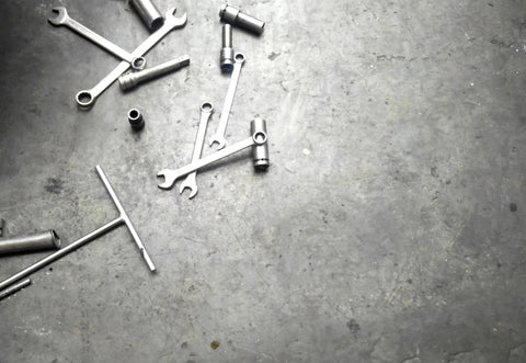 Wrenches and sockets scattered on a concrete floor, tools for mechanics and auto technicians in a workshop setting.