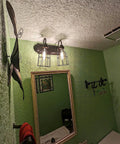 Premium Black Metal Wire Cage Lamp Guard For Ceiling Fans And Pendant Lights Killer Diamond Shape Light Cover with two bulbs showcased above a mirror