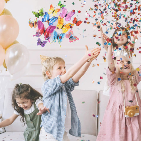 Kids celebrating at a party with Colorful 3D Butterfly Wall Decor Set With Magnets And Glue Dots Dual Attachment in the air.