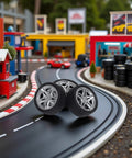 Four Piece 48MM Rubber Toy Car Wheel Set For RC Models displayed on a toy race track, showcasing dope black simulation wheels.
