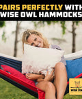 Woman smiling and relaxing in a hammock outdoors, cuddling a pillow, featuring Wise Owl Outfitters logo at the corner.
