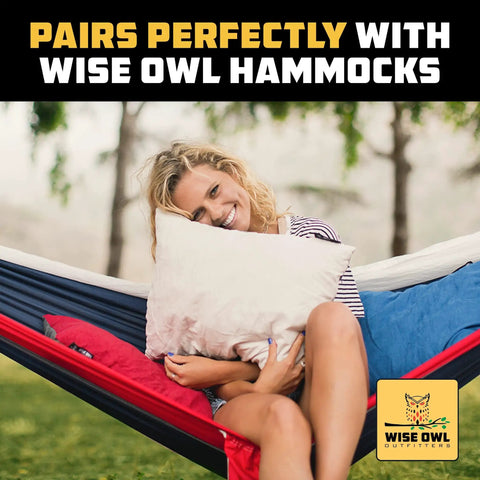 Woman smiling and relaxing in a hammock outdoors, cuddling a pillow, featuring Wise Owl Outfitters logo at the corner.