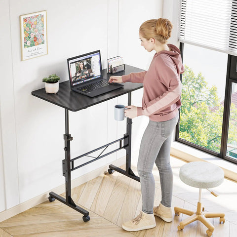 Person working at 32 Inch Portable Standing Desk On Wheels, Adjustable Height Sit Stand Desk For Small Spaces, Black