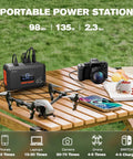 Go To Portable Power Station 98Wh Solar Generator for camping on table with camera and drone in outdoor setting